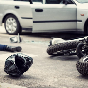 Motorcycle and black helmet on ground next to car after dangerous accident - Legal Advantage Group