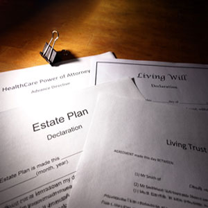 A stack of estate planning documents including wills, trusts, and power of attorney forms on a wooden desk symbolizing estate planning before international travel - Legal Advantage Group