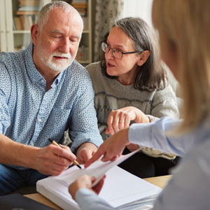 Couple reviewing documents with an advisor, discussing long-term care and Medicaid planning